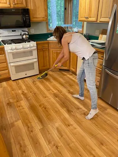 An image of a lady meticulously cleaning kitchen floors