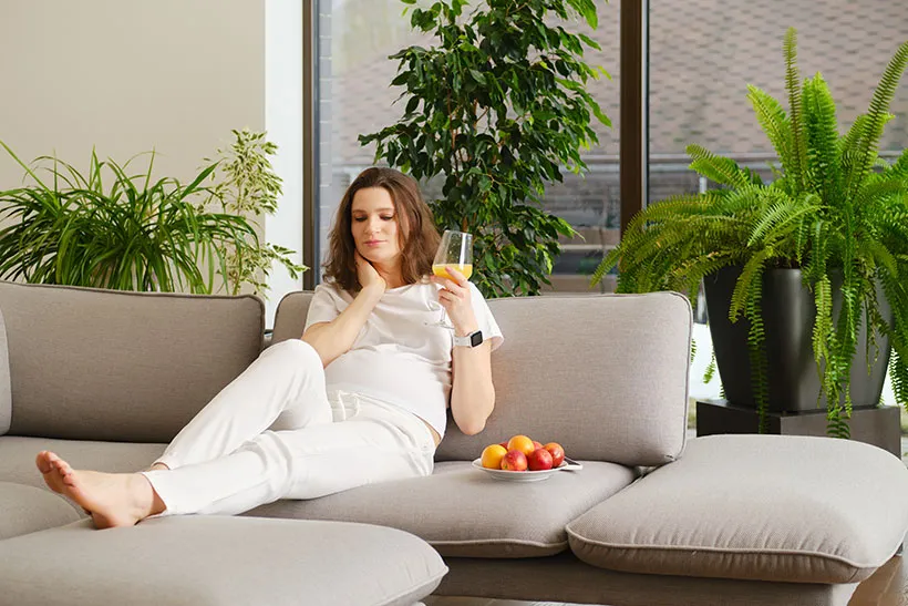 Middle aged woman relaxing on home drinking mango juice